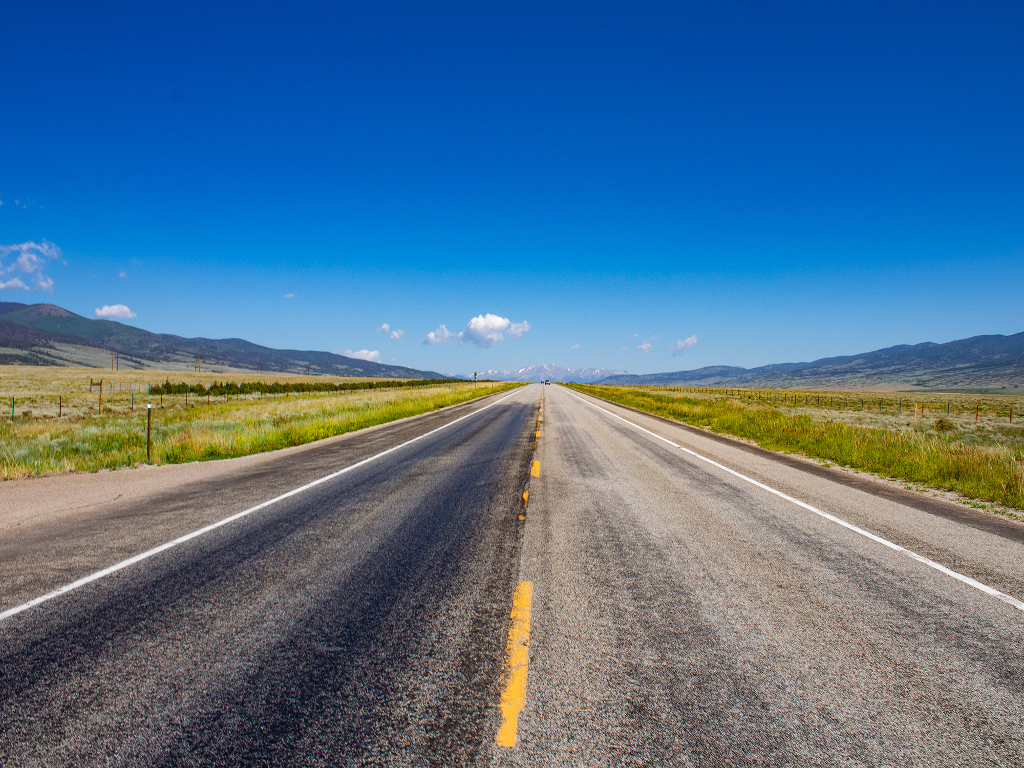 An inspiring view of an open, empty road that vanishes into the mountains in Colorado
